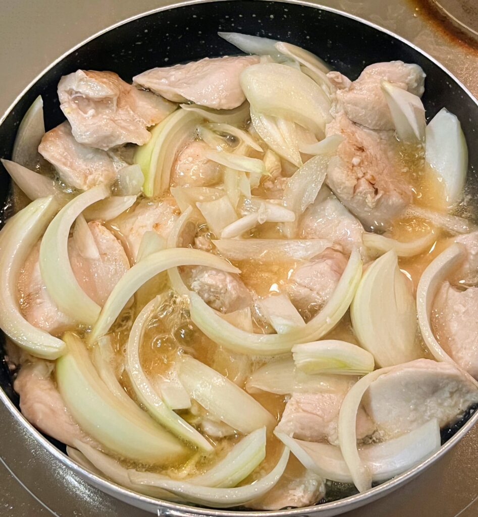 鶏胸肉と玉ねぎを煮込んでいる写真